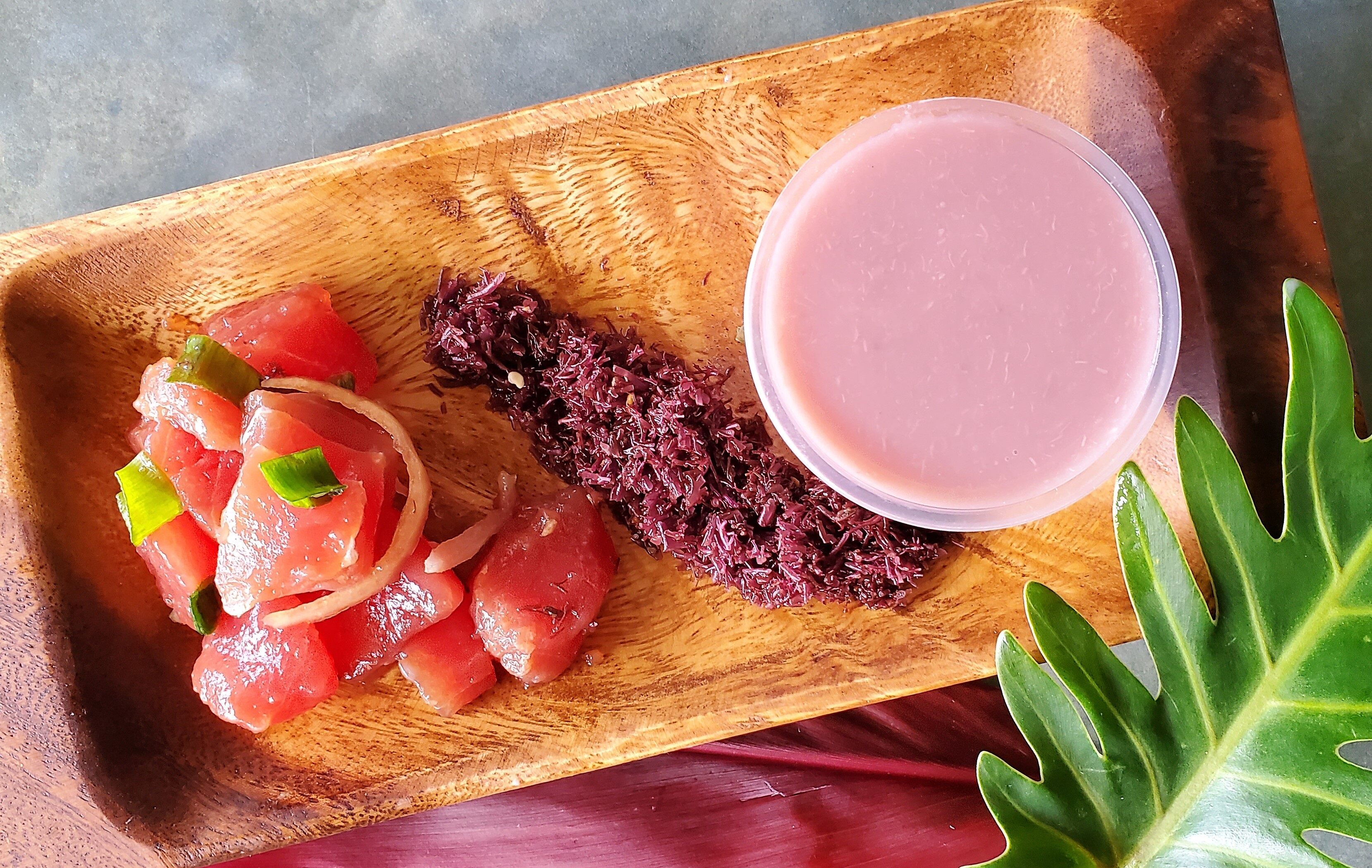 Photo of a bamboo plate containing Hawaiian poke (fish), limu (seaweed) and poi (pounded taro)
